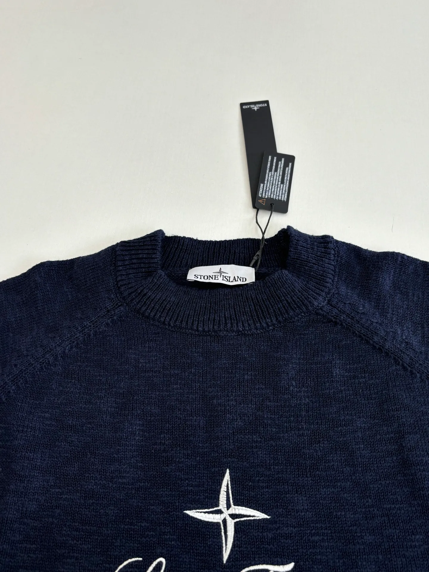 P460 STONE ISLAN*/Stone Island FW25 Holiday Limited Threaded logo embroidered pullover knitted sweater. The fabric is made of imported ultra-fine merino wool yarn, which has been combed to remove impurities and anti-pilling. The plain base is woven with a 14-needle circular machine. The yarn is first dyed and then woven to make the navy blue color rich and not easy to fade. The body is designed with a raglan sleeve structure, the shoulder panels are laser positioned and cut, and the splicing joints are seamlessly connected using embedded clip technology, giving you a non-restrained feeling when worn. The brand logo and star pattern on the chest adopt a combination of hand-applied embroidery + flat embroidery, using high-elastic polyester-cotton thread. The stitch density is controlled at 8 stitches per centimeter. The outline of the pattern is clear and three-dimensional, and it is wear-resistant and does not fall off. The neckline is designed with a ribbed round neck. The rib tissue is pre-shrunk and shaped by high temperature. It has excellent resilience and is not easy to loosen. The cuffs and hem are also ribbed with the same material, and are reinforced with the body through overlock sewing technology. The overall tailoring follows ergonomics, and each process undergoes quality control testing. From yarn weaving to finished product sewing, the precision of details is controlled throughout the process to create knitted items with both functionality and design. The overall wiring is straight and delicate, the fabric is comfortable and soft, and the color is consistent without color difference. Size: S/M/L/XL